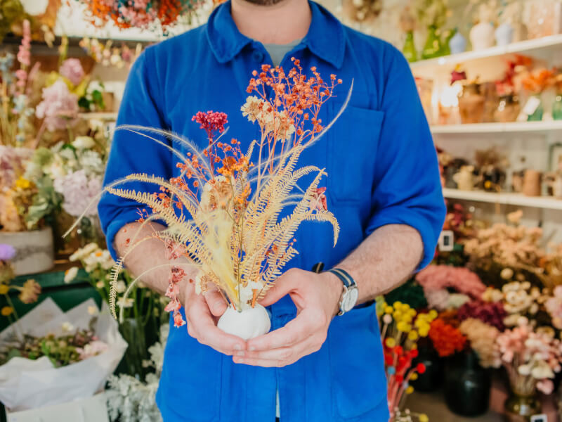 A man holds a dried flower arrangement